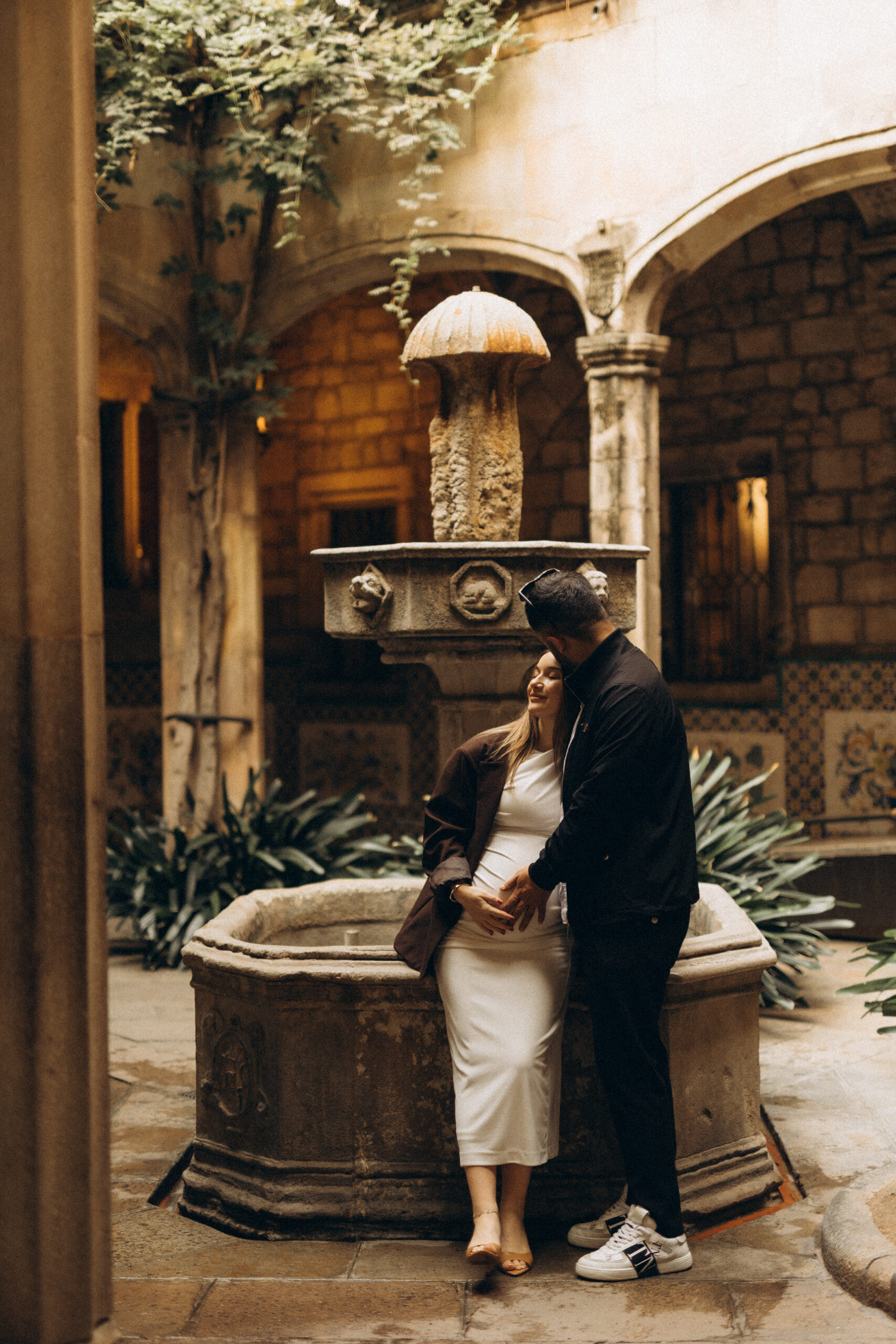 a pregnant couple is hugging in the icónico spot of the GOTHIC QURTER IN BARCELONA. Casa de l Adriaca